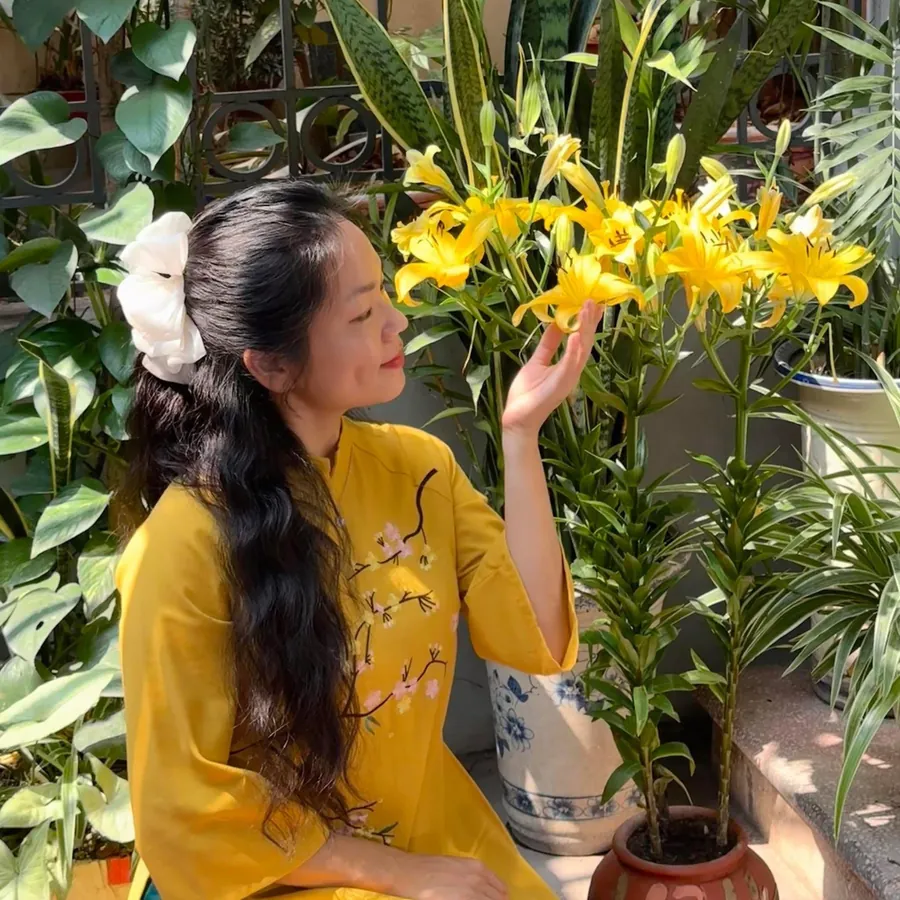 Đỗ Thị Bích Ngọc trong tà áo dài vàng bên chậu hoa ly